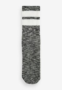 Svart och vit randig knä-lång strumpa, med en strukturerad stickdesign, ribbad fåll och en solid mörk kropp.