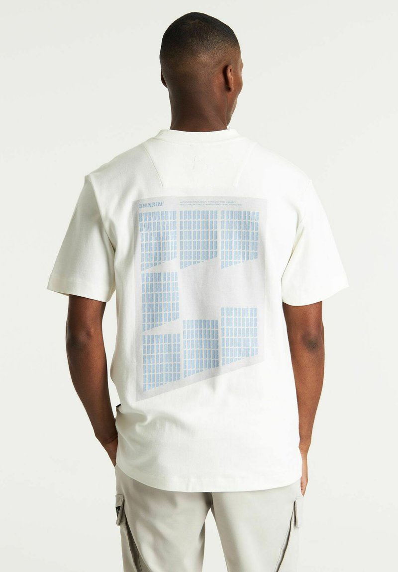 T-shirt bianco in cotone con vestibilità rilassata, caratterizzato da un motivo a rete blu chiaro sul retro. Maniche corte e scollatura classica a girocollo.