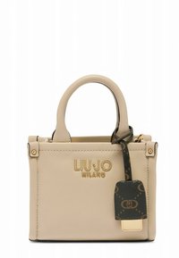 Bēšas krāsas ādas rokassoma ar īsām rokturiem, zelta logotipu un tumšu rakstainu birku. Izceļas ar stingru dizainu un minimālu aparatūras akcentu.