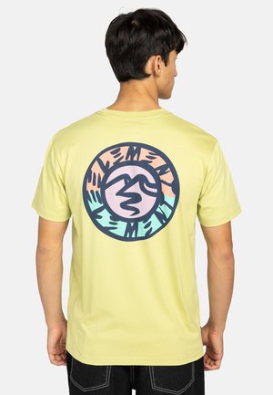 Lichtgele t-shirt met een grote ronde graphic op de achterkant, met kleurrijke abstracte ontwerpen in roze, blauw en zwarte lijnen.