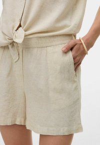 Linnen shorts in lichtbeige met een losse pasvorm, voorzien van zijzakken, plooien en een geknoopte strikdetail in de taille. Zachte textuur.