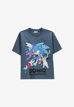 Niebieska koszulka z Sonic the Hedgehog w dynamicznej pozie, z kolorowymi plamami i napisem „SONIC THE HEDGEHOG” pod postacią.