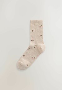 Șosetă bej din bumbac cu modele mici florale verzi și roz, tiv nervurat și vârf rotunjit. Textură moale și grosime medie.