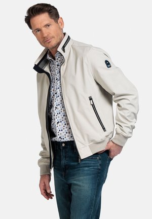 Lichtgekleurde, ritsbomberjack met een gestructureerde kraag, elastische manchetten en een patch op de linkerarm. Gedragen over een gestreept shirt en denim jeans.