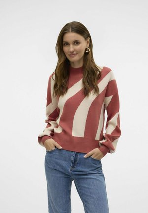 Rood en crèmekleurig gestreept trui met een hoge halslijn en losse mouwen, gecombineerd met blauwe spijkerbroeken. Zachte textuur en casual pasvorm.