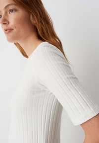 Witte geribbelde top met een textuurdesign, bootnek, en mouwen tot de elleboog, met een aansluitende pasvorm en zachte stof.