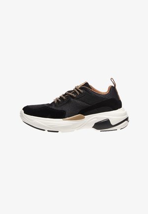 Black and tan sneaker with a textured surface, featuring black laces, a chunky white sole, and a back tab for easy wear.