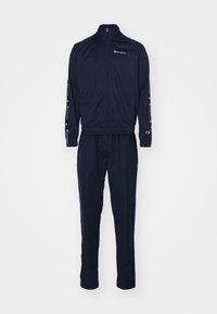 Survêtement Champion bleu marine avec veste zippée et pantalon assorti, avec des détails du logo sur la poitrine, les manches et la jambe du pantalon.