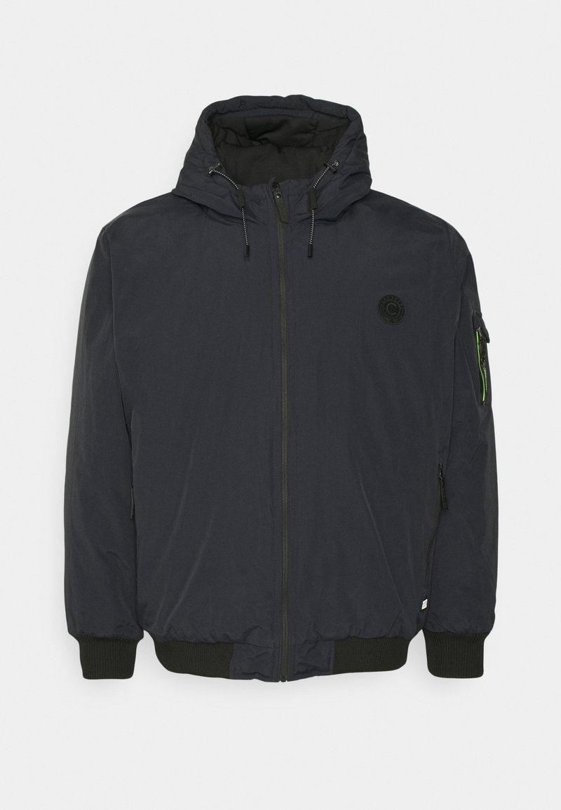 Dark blue padded jacket with a hood, front zipper, ribbed cuffs, and a logo patch on the chest. Features a pocket on the sleeve.