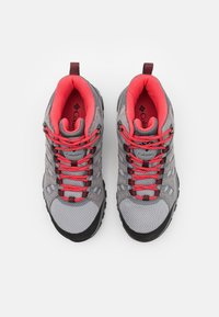 Grå vandringsskor med en meshuvtrupp, röda detaljer och svarta gummisulor. Har framträdande snörning och en vadderad krage för komfort.