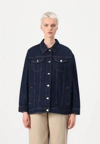 Temno modra jeans jakna z gumbastim zapiranjem spredaj, dvema prsnikoma in ovratnikom. Ima srebrno kovinsko opremo in vidne detajle šivanja.