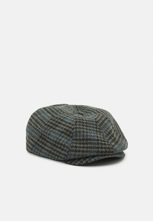 Casquette plate en tweed avec un motif pied-de-poule noir, bleu et gris, présentée sur un fond blanc.