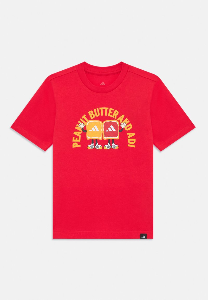 Red cotton t-shirt with short sleeves, featuring a graphic of two stylized sandwich characters and the text "PEANUT BUTTER AND ADI" in yellow.