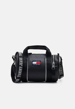 Bolso de deporte cilíndrico negro con acabado texturizado, acentos en blanco, asa superior, correa ajustable y un parche de logo en la parte frontal.