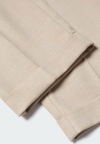 Beżowa bawełniana tkanina o prążkowanej fakturze, z starannie złożonymi krawędziami i widocznym przeszyciem, podkreślająca czysty i prosty design.