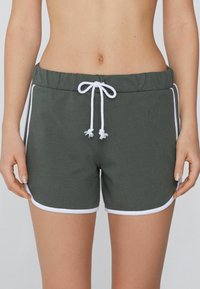 Donkergroene shorts van een zachte, ademende stof. Voorzien van een witte trekkoord, witte bies aan de benen en een elastische tailleband.