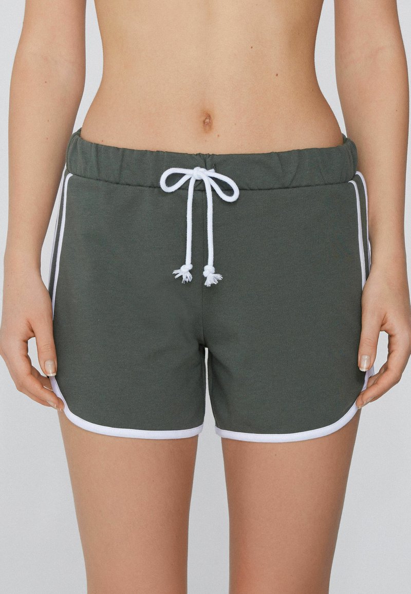 Donkergroene shorts van een zachte, ademende stof. Voorzien van een witte trekkoord, witte bies aan de benen en een elastische tailleband.