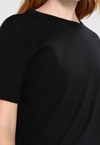 Black cotton T-shirt with a round neckline and short sleeves. Smooth texture with minimal seams and a fitted design.