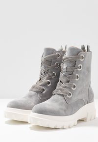 Stivaletti alla caviglia in suede grigio con punte rotonde, occhielli in metallo e lacci grigi. Suole in gomma bianca spessa con design a battistrada, dotati di linguette posteriori per il sollevamento.