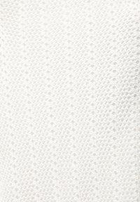 Gros plan sur un tissu tricoté blanc avec un motif texturé et répétitif de petites boucles et une apparence douce.