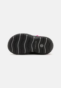 Semelle de chaussure en caoutchouc noir avec des motifs texturés, des accents gris et des trous de drainage. Présente le logo Geox et un design de grip contourné.
