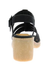 Sandal negro con tiras y hebilla, que presenta un tacón texturizado en color beige y una planta lisa. Las tiras tienen un diseño abierto para mayor transpirabilidad.