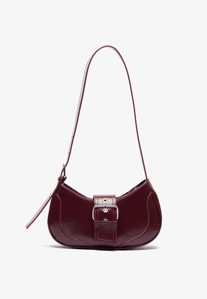 Pequena mala de ombro em pele burgundy com uma alça longa e um detalhe de fivela na frente, contra um fundo simples.