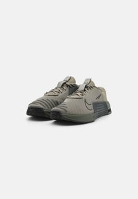 Nike atletiksko i olivengrøn, med en struktureret mesh-overdel, flade snørebånd og en polstret sål med et mønstret gummistød.
