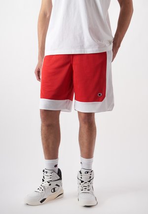 Rote Basketballshorts mit weißen Mesh-Akzenten, strukturiertem Stoff und einem Logopatch. Kombiniert mit weißen Turnschuhen und gemusterten Socken.