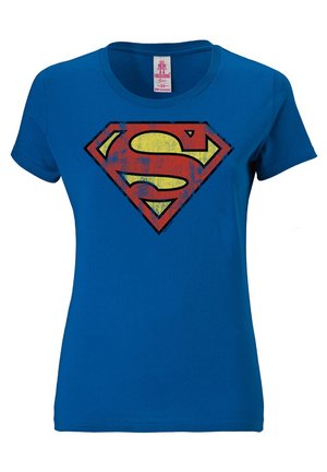 T-shirt en coton bleu avec un grand logo Superman rouge et jaune usé sur le devant, avec un col rond et des manches courtes.