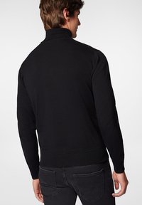 Czarny sweter z dzianiny z wysokim kołnierzem, prążkowanymi mankietami i dolnym brzegiem, prezentujący dopasowany krój i gładką fakturę. Widok z tyłu.