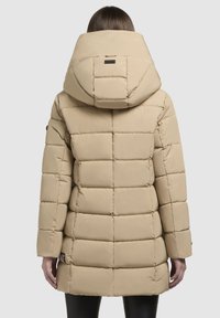 Beige pufferjakke med en udtalt hætte, der har et quiltet design, lange ærmer og en mellemlang længde. Glat tekstur med logo accenter.