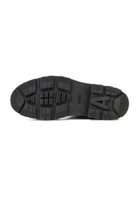 Zwarte rubberen zool met diepe profielen voor grip. Heeft verhoogde secties voor tractie en een reliëf merklogo. Duurzaam en gestructureerd oppervlak.