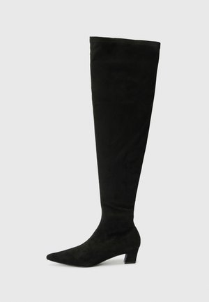 Bottes noires au-dessus du genou en daim doux, avec un bout pointu et un talon bloc bas. Texture lisse avec un design ajusté.