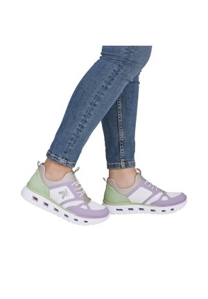 Person trägt blaue enge Jeans und pastellgrüne, violette und weiße Sportsneaker mit weißen Sohlen.