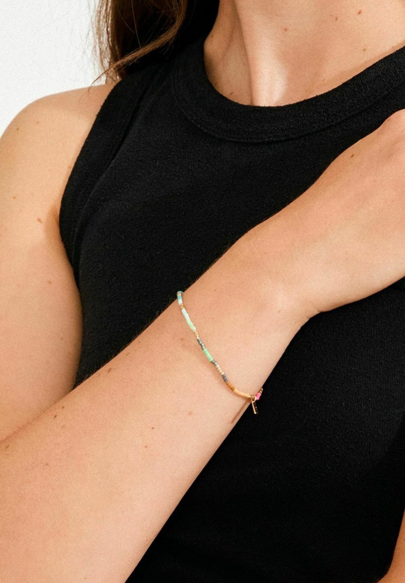 Bracelet coloré en perles avec diverses formes dans des tons turquoise, marron et rose. Comprend un fermoir doré pour la fixation.