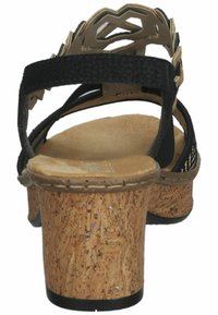 Zwarte haksandalen met kurken platform, gestructureerde bovenste banden en uitsnijdingen. Vloeiende tan zolen en stevige hak voor ondersteuning.