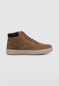 Botas de tobillo de ante marrón con un cuello de tela negra texturizada, que cuentan con ojales de metal y una suela de goma de color claro.