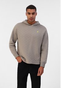 Hallgrey quiltitudega kapuutsiga särk, küljel tasku, sooniku varrukad ja kerge kollane logo rinnal. Seljas mustad püksid.