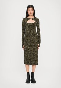 Long-sleeve, leopard print dress in dark green and black, featuring a front cut-out detail. Worn with black ankle boots.