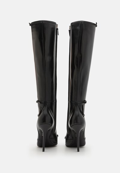 Botas negras hasta la rodilla de cuero brillante, con tacón de aguja y cremalleras laterales, adornadas con detalles decorativos cerca de la parte superior y el tacón.