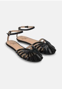 Schwarze Sandalen mit Riemen, einem geflochtenen Design und strukturiertem Finish. Verfügt über Knöchelriemen und eine flache Sohle für Komfort.