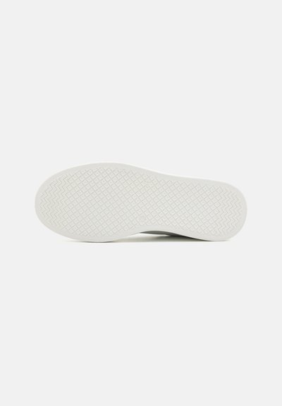 Semelle de chaussure en caoutchouc blanc présentant un motif texturé avec des formes en zigzag et en diamant, conçu pour offrir adhérence et traction.