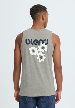 Grå ærmeløs skjorte med en stor mørkeblå "blend"-logo og tre hvide blomsterdesign med mørke centre på ryggen. Bomuldsmateriale.