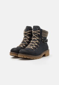 Bottes de randonnée noires avec un extérieur en daim, un col en feutre gris, des lacets beige et une semelle en caoutchouc résistante. Renfort au niveau des orteils et détails de boucles.