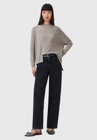 Pullover grigio chiaro a maglia testurizzata con design asimmetrico abbinato a jeans neri a gamba dritta ad altezza vita e scarpe nere basse.