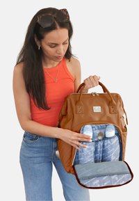 Bolso de pañales de imitación cuero marrón con dos asas; el interior azul claro cuenta con bolsillos aislantes para biberones y un gran compartimento con cremallera.