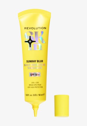 Gelbe Kunststofftube von Revolution Sunray Blur Sonnencreme mit holografischem Text, ausgestattet mit einer spitzen Düse und einem passenden gelben Deckel.