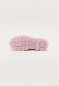 Pink rubber shoe sole featuring a zigzag pattern, textured grip, and a circular logo detail. The design emphasizes traction and durability.