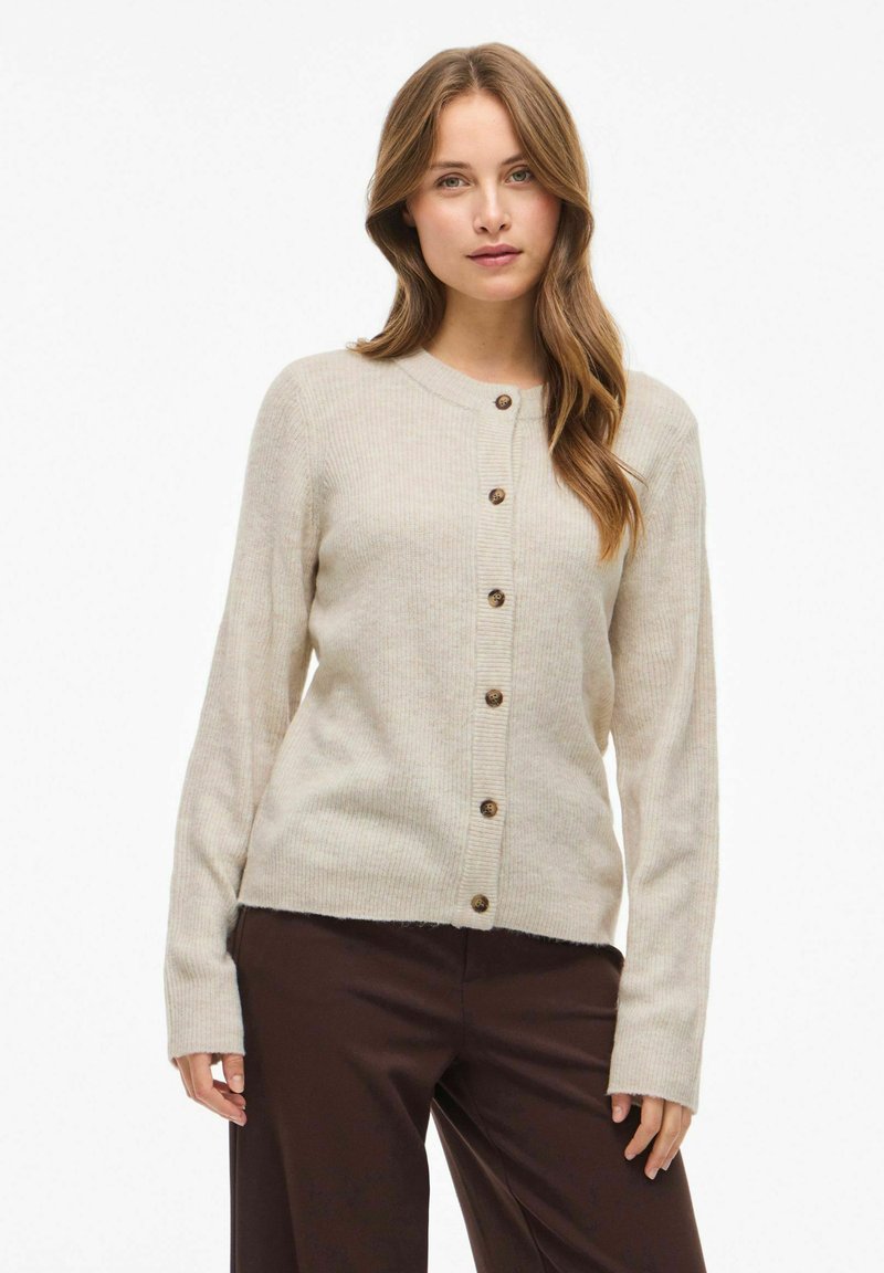 Cárdigan beige de canalé con cuello redondo, cierre delantero de botones y mangas largas, que presenta botones de madera natural y una textura suave.